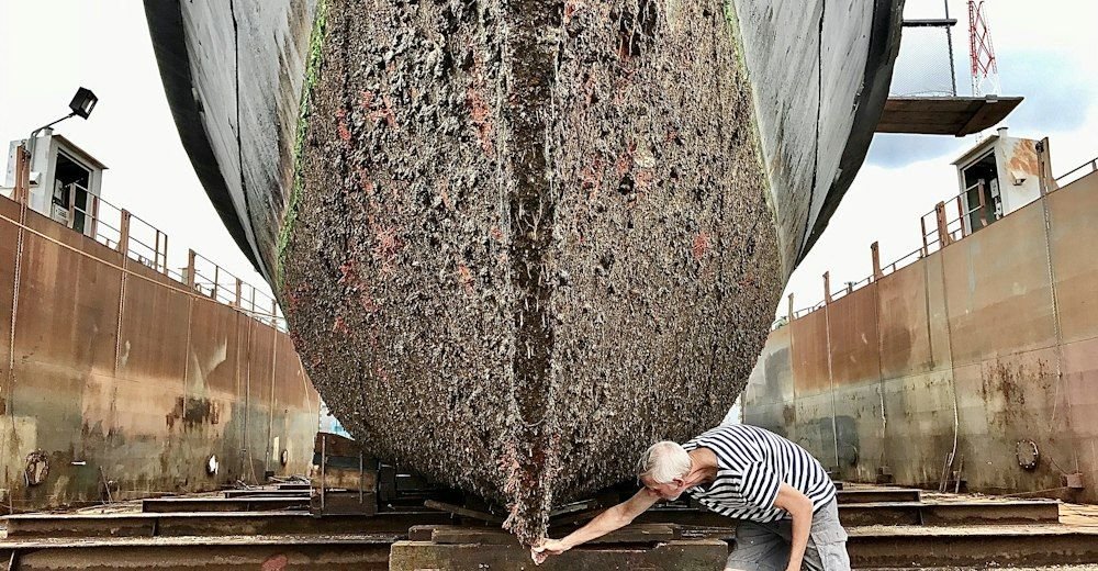 Casco de un barco en dique seco con un operario trabajando