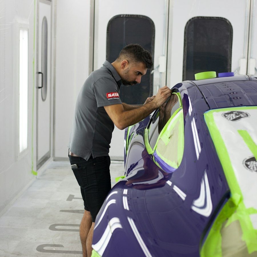 Pintor preparando la carrocería en una cabina de pintura
